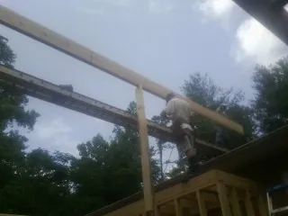Carpenter setting a ridge beam over a new addition frame — Ice Dam Removal by Roofing Brothers in Loris