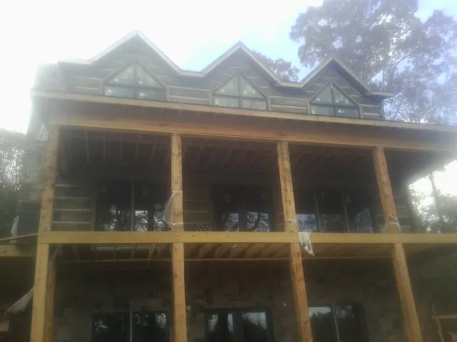 Dormers and porch framing on a large log home under construction — Roof Coating work by our crew in Loris