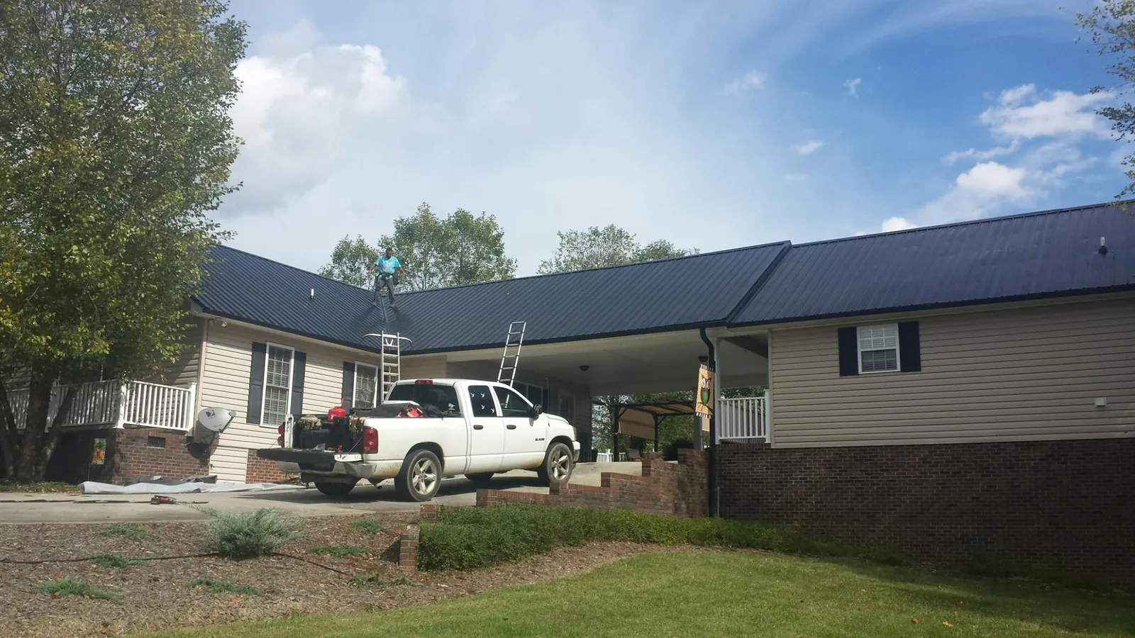 Black metal roof over a home and attached breezeway with ladders set in Loris