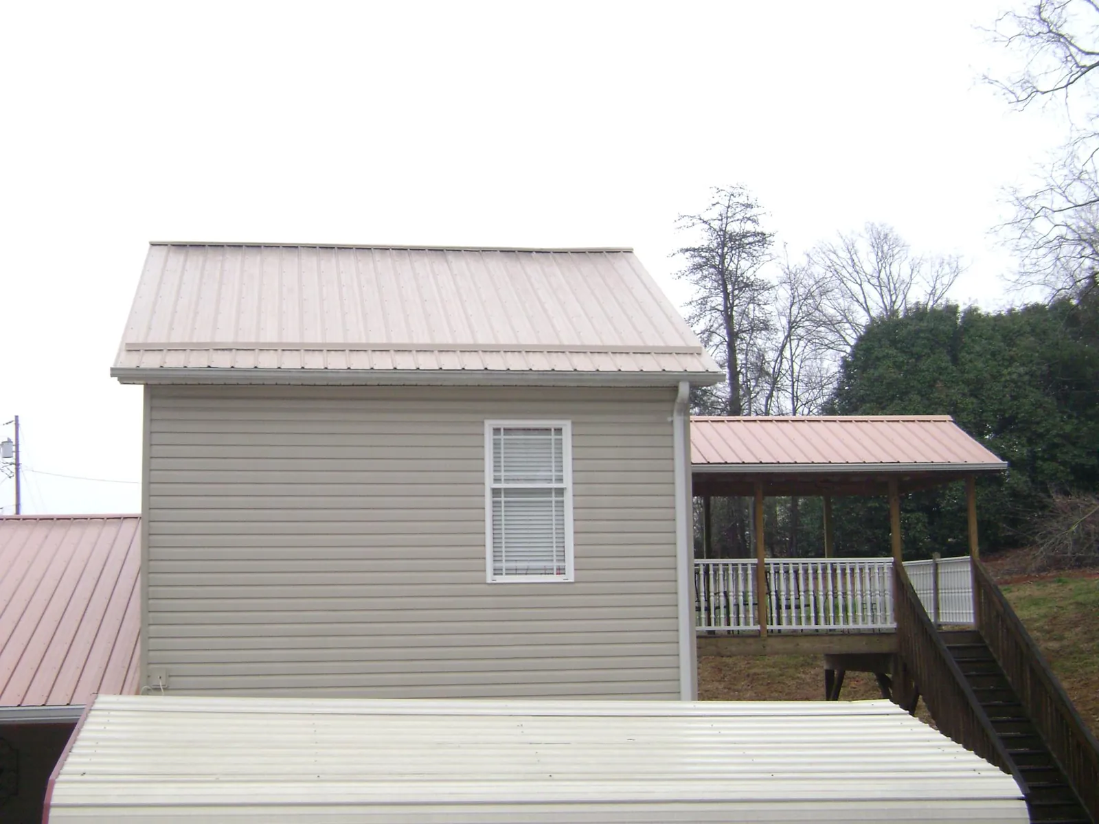 Tan metal roofs on a two story addition and attached porch, from a Roof Replacement job in Loris